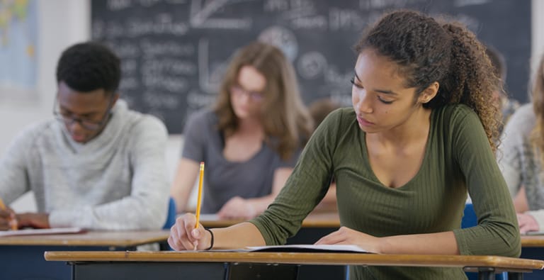 A mixed race teenage girl is taking a high school standardized test in class.